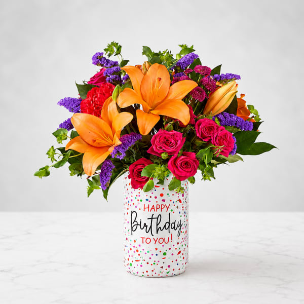 Bouquet of orange lilies and pink roses in a birthday vase