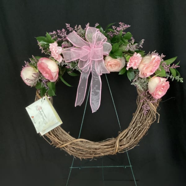 Pink floral wreath with a ribbon bow on a twig base