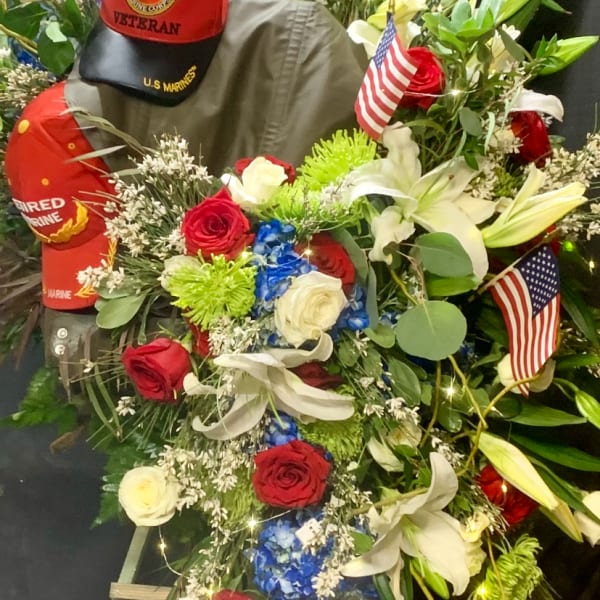 Large patriotic floral wreath with roses, lilies, and American flags