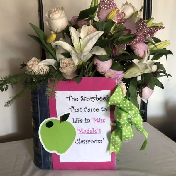 Bouquet of white lilies and pale roses in a decorated book-shaped container