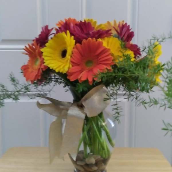 Bouquet of colorful gerbera daisies in a glass vase with a ribbon