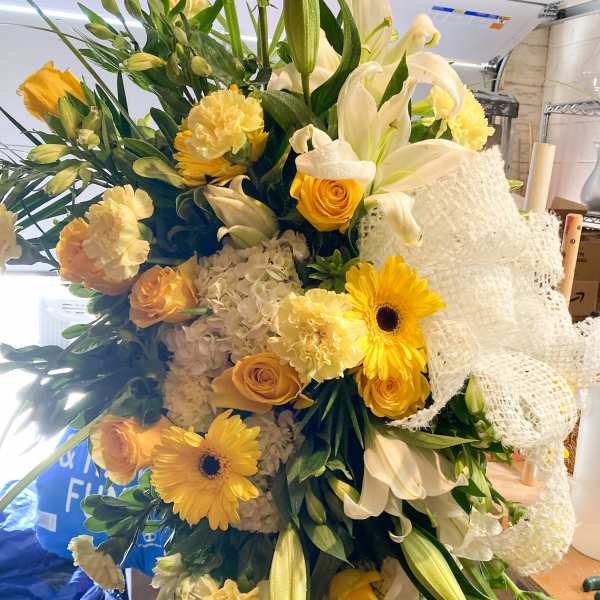 Large bouquet of yellow and white flowers with a white mesh ribbon