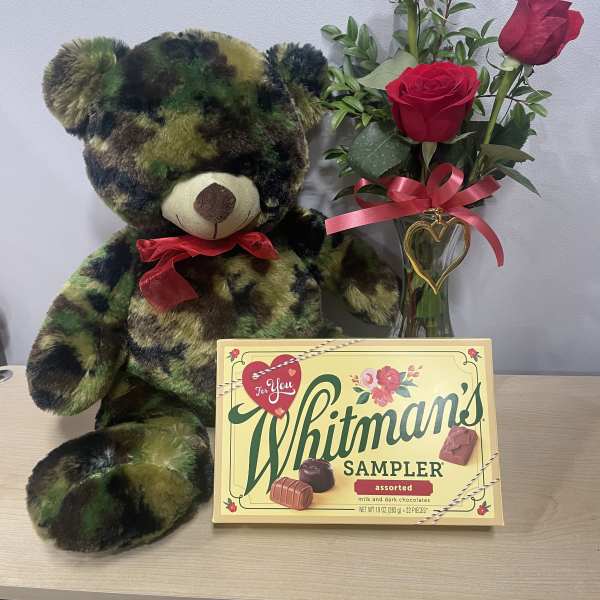 Teddy bear beside red roses in a glass vase and a Whitman's chocolate box