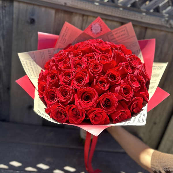 Bouquet of red roses wrapped in pink and cream paper