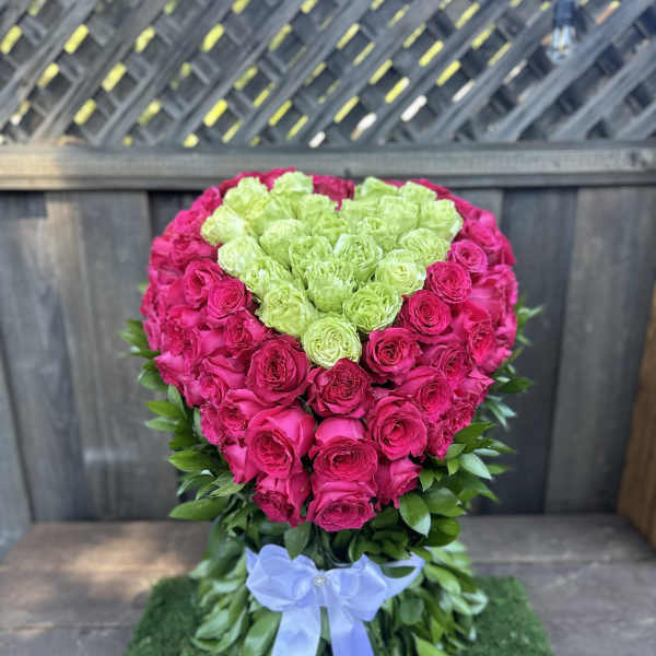 Heart-shaped rose arrangement in hot pink and lime green with a blue ribbon