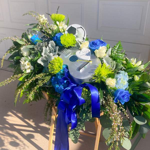 Floral arrangement around a guitar-shaped centerpiece with blue ribbon
