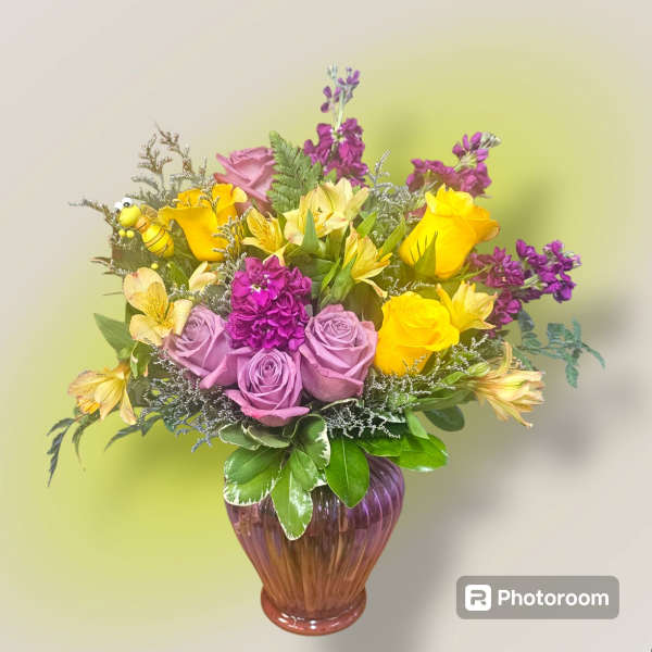 Bouquet of yellow and lavender roses in a purple glass vase