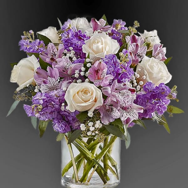 Purple and white bouquet of roses and alstroemeria in a glass vase