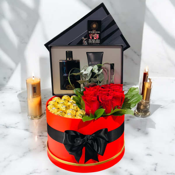 Red roses and chocolates in a round gift box with perfume and candles