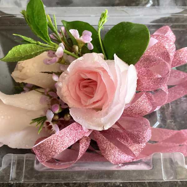 Pink rose boutonniere with glittery ribbon in a clear plastic box
