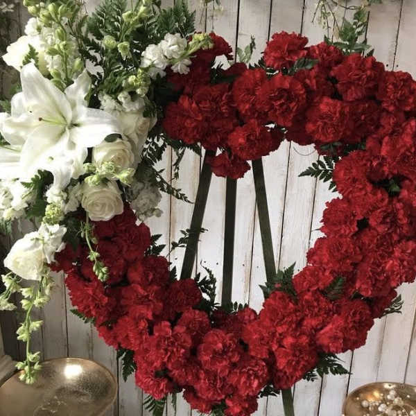 Heart-shaped floral wreath with red and white flowers on a stand