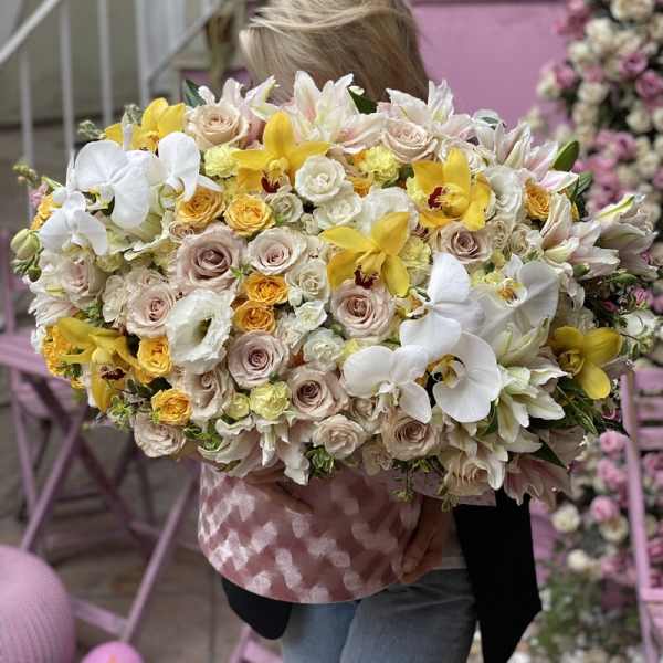 Large bouquet of white, cream, and yellow flowers held by a person