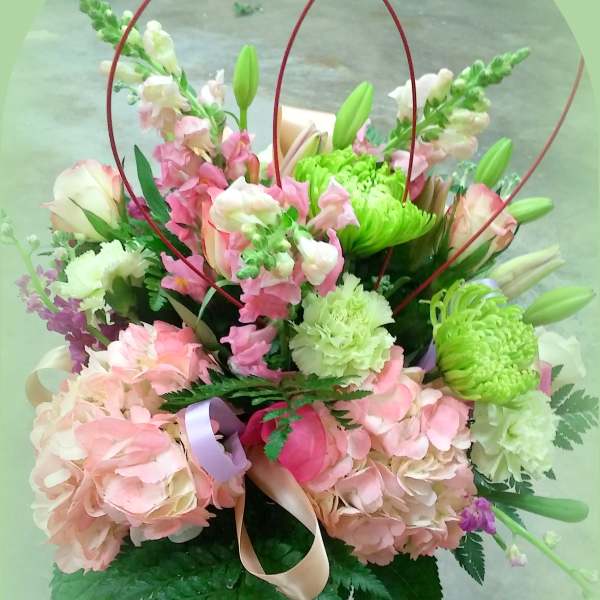 Pink and green mixed bouquet in a glass vase with ribbon loops