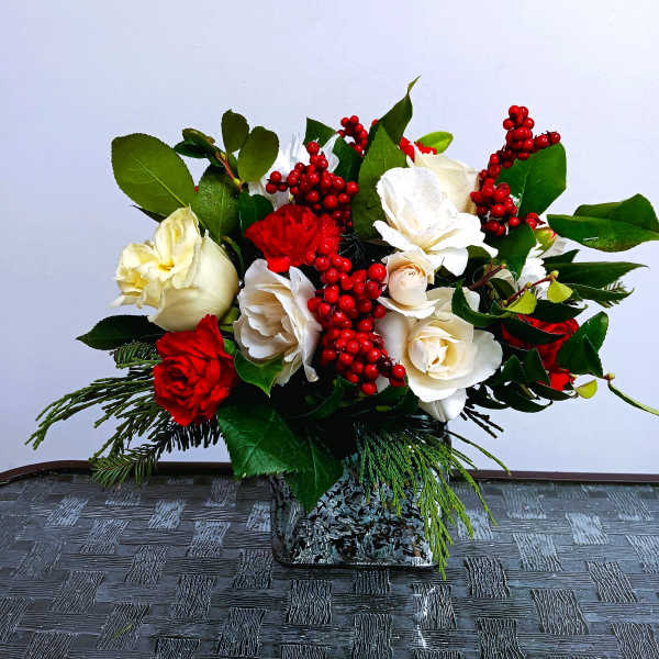 Red and white rose arrangement in a square glass vase