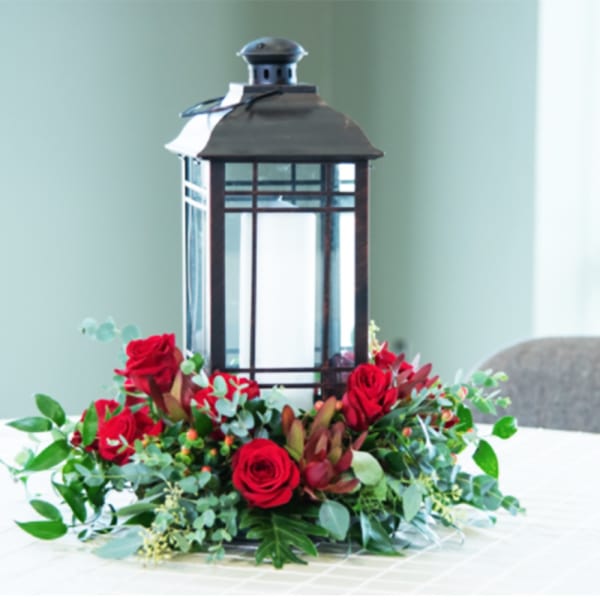 Red roses arranged around a black lantern centerpiece