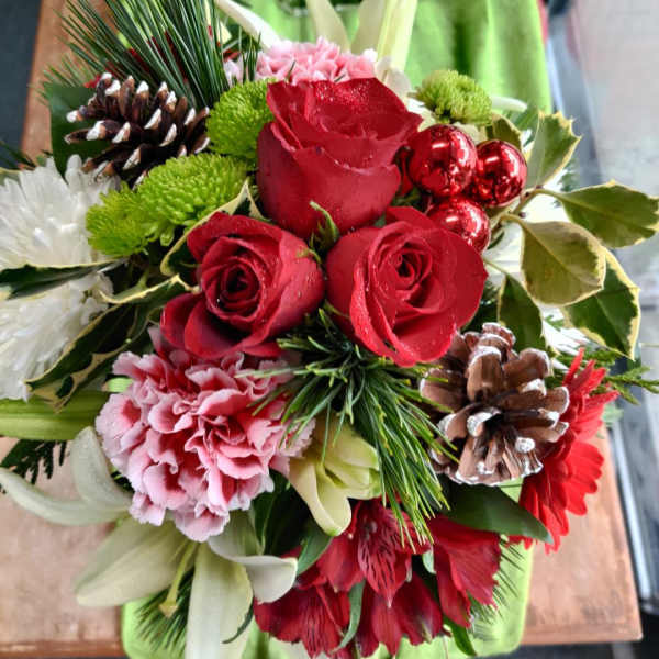 Bouquet of red roses, pink carnations, and white lilies with pinecones