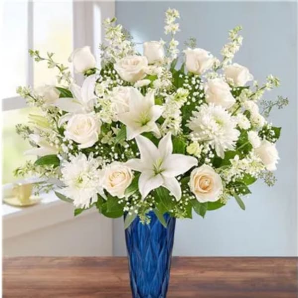 White roses and lilies in a blue glass vase
