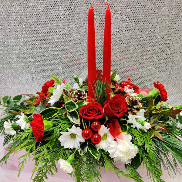 Red candles in a holiday floral centerpiece with roses and white blooms