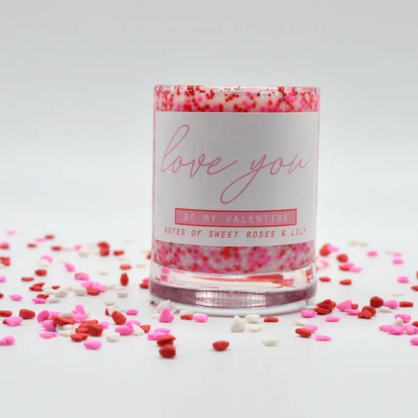 Pink candle in a glass jar with confetti around it