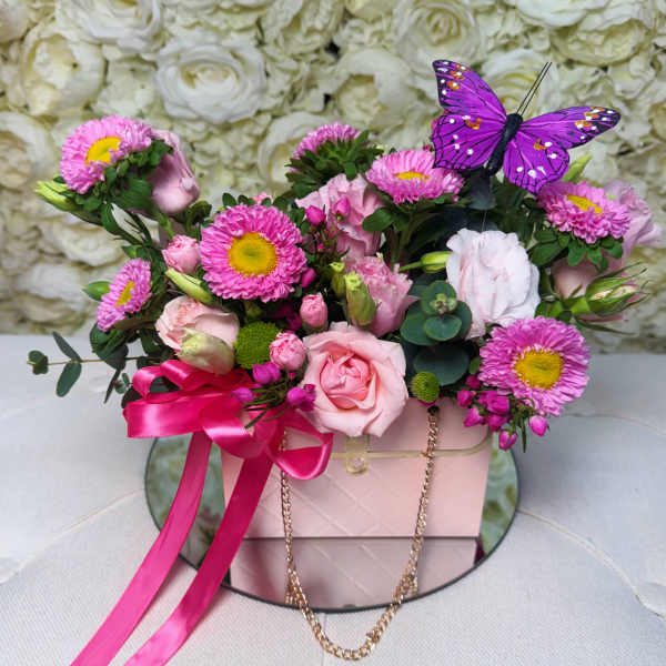 Pink and white flower arrangement in a blush box with a purple butterfly