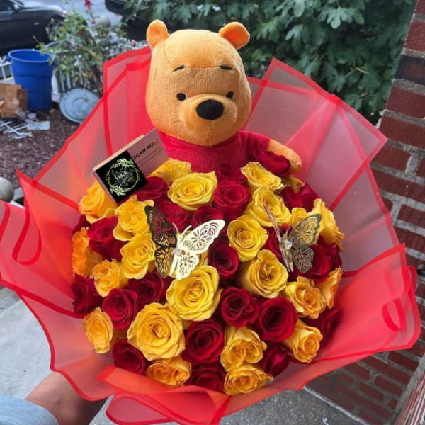 Bouquet of red and yellow roses with a Winnie the Pooh plush