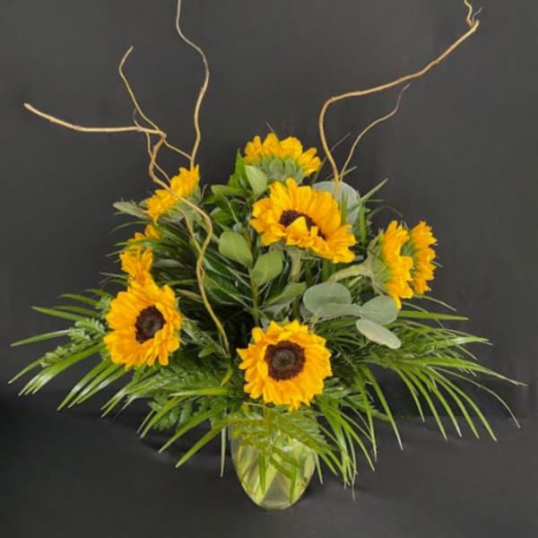 Sunflower arrangement in a glass vase with curly branches