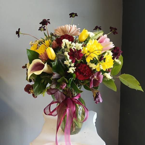 Mixed bouquet in a glass vase with yellow, pink, and burgundy flowers