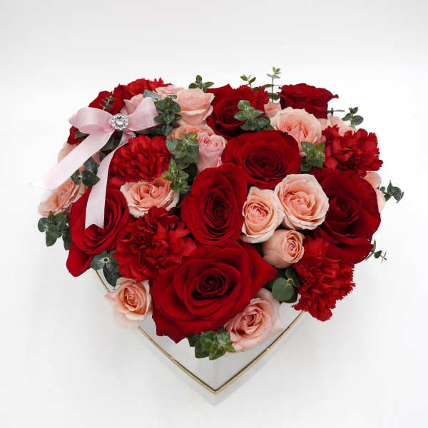 Heart-shaped box of red and blush roses with a pink ribbon