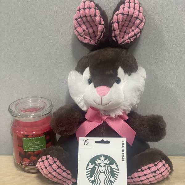 Plush bunny with a pink ribbon beside a candle and Starbucks gift card