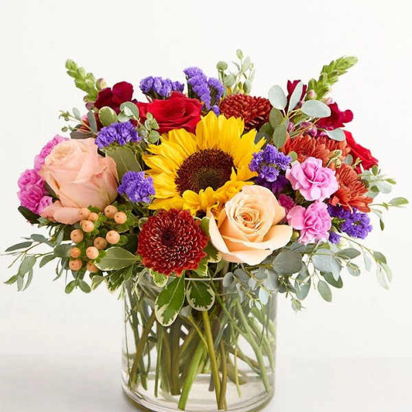 Mixed bouquet with sunflowers, roses, and chrysanthemums in a glass vase