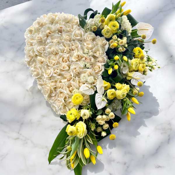 Heart-shaped bouquet of cream and yellow flowers on a marble surface