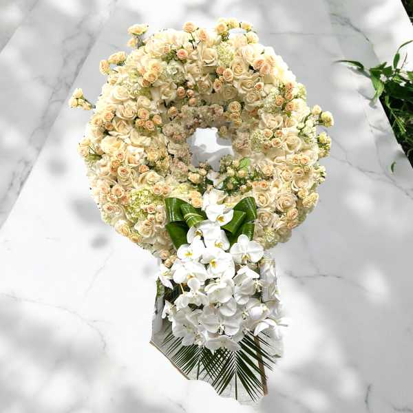 Large cream rose wreath with white orchids and a green ribbon