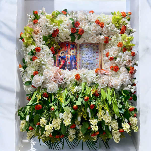 Large floral tribute framing an open book with white and orange flowers