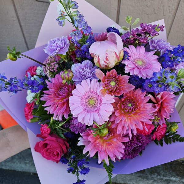 Bouquet of pink, purple, and blue flowers wrapped in lavender paper