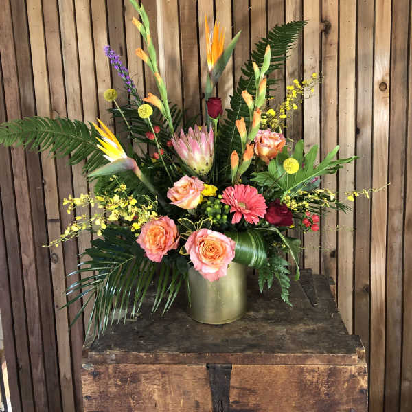 Tall tropical bouquet with orange and pink flowers in a gold vase