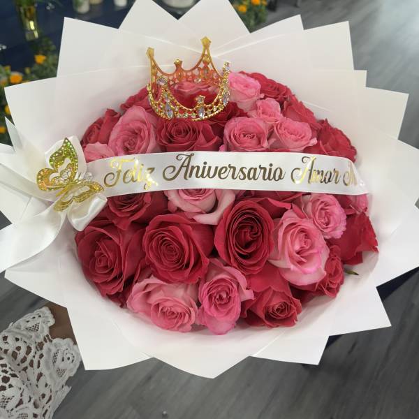Pink and red rose bouquet with a decorative crown and anniversary ribbon