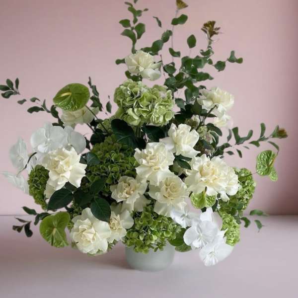 White and green floral arrangement in a pale vase