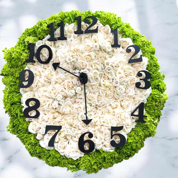 Round floral clock made of white roses with green edging and black numbers