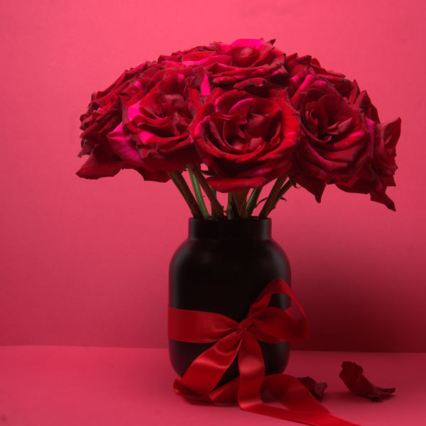 Red roses in a black vase with a red ribbon