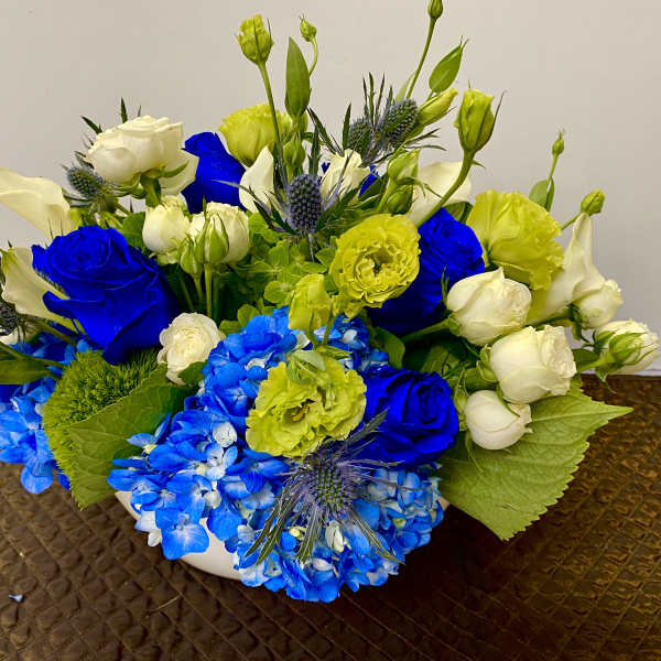 Blue and white floral arrangement with yellow accents in a white bowl
