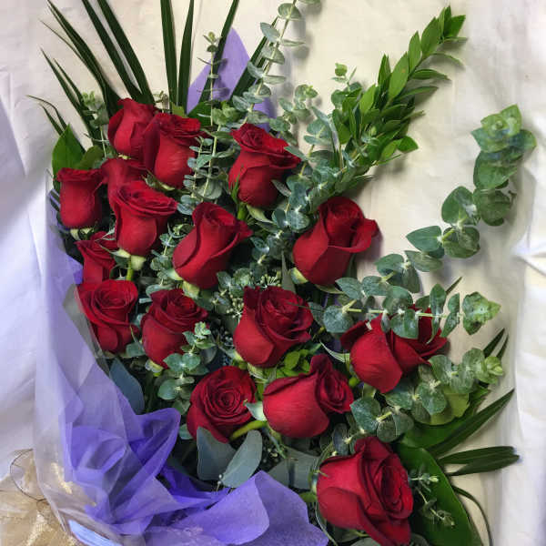 Bouquet of red roses with eucalyptus and purple wrapping