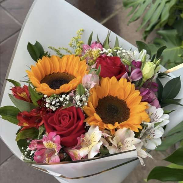 Bouquet of sunflowers, red roses, and mixed pastel flowers wrapped in white paper