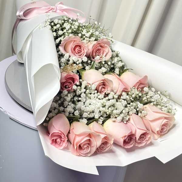 Pink roses with baby's breath in white wrapping and a pink ribbon