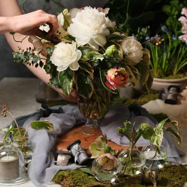 White and blush floral arrangement in a glass vase with small glass bud vases nearby