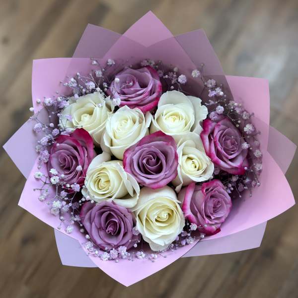Bouquet of pink, purple, and white roses wrapped in pink paper