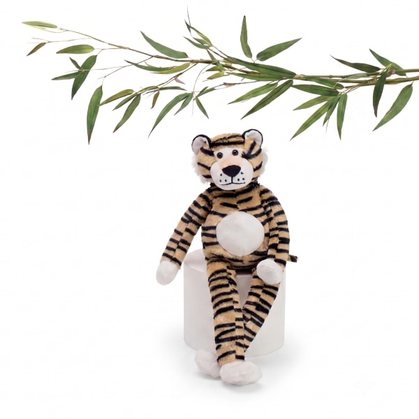 Plush tiger sitting on a white cylinder with a bamboo branch above