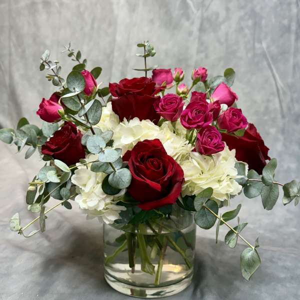 Red and pink roses with white hydrangeas in a glass vase