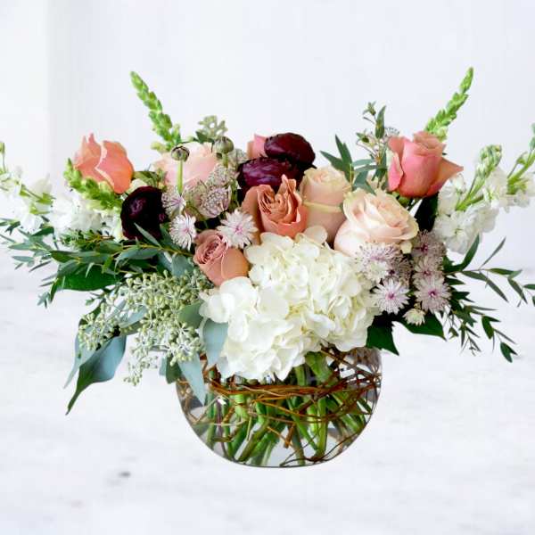 Mixed bouquet of blush and white flowers in a glass vase