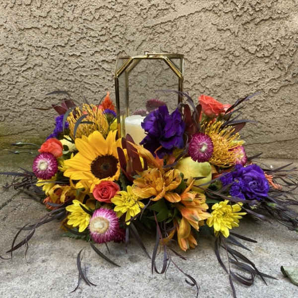 Colorful floral arrangement around a lantern with a candle