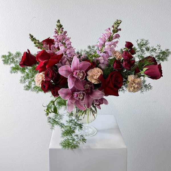 Pink orchids and red roses arranged in a clear glass vase